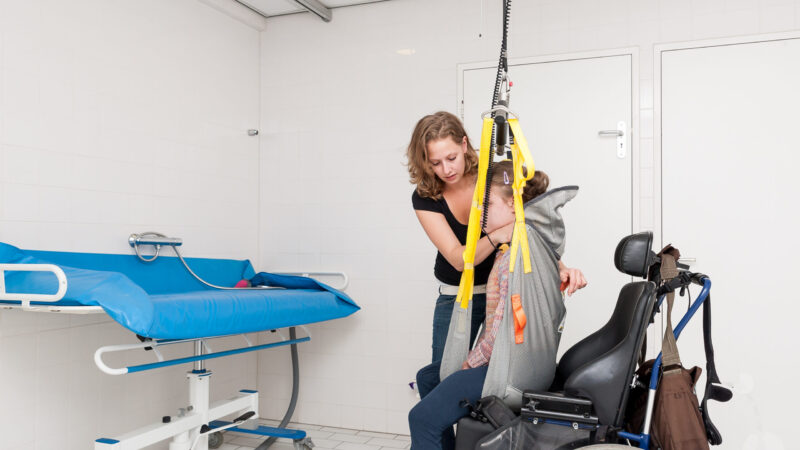 A disabled child in a wheelchair being cared for A disabled person in a wheelchair being lifted using a special needs lift with help from a special needs carer image shows working with disabled people